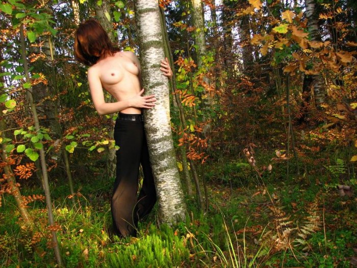 Shy redhead posing topless at forest