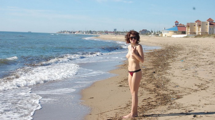 Nice girl in sunglasses posing topless at the beach