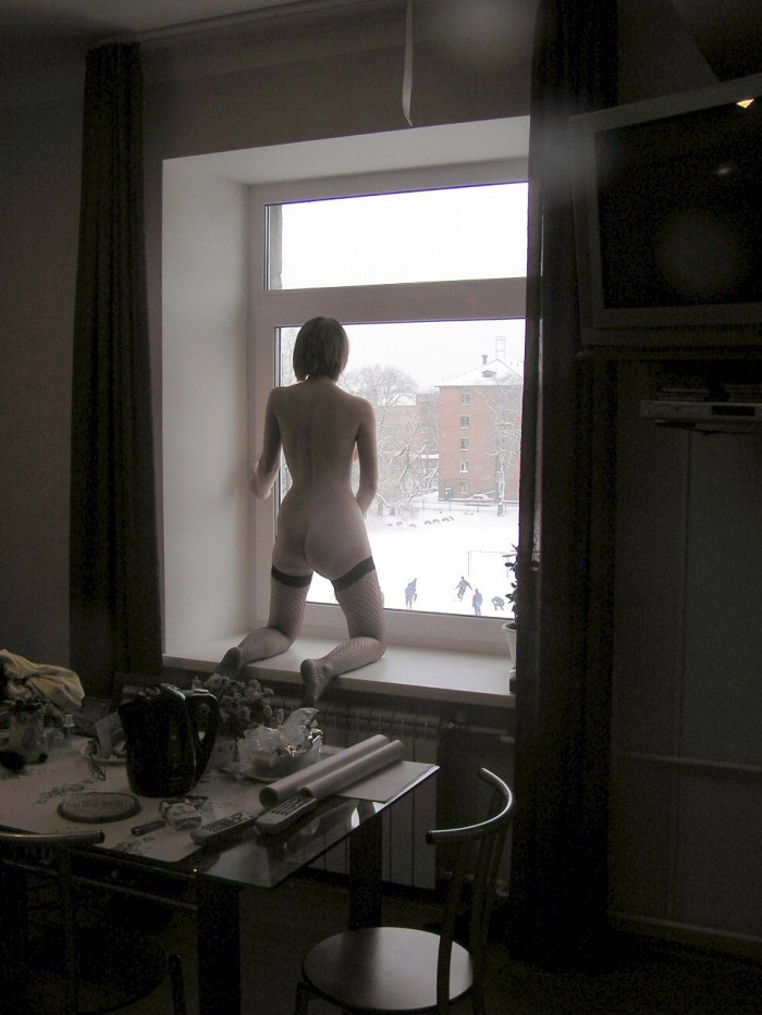 Hot teen harlot stands on a windowsill to show her nude body to public.jpg