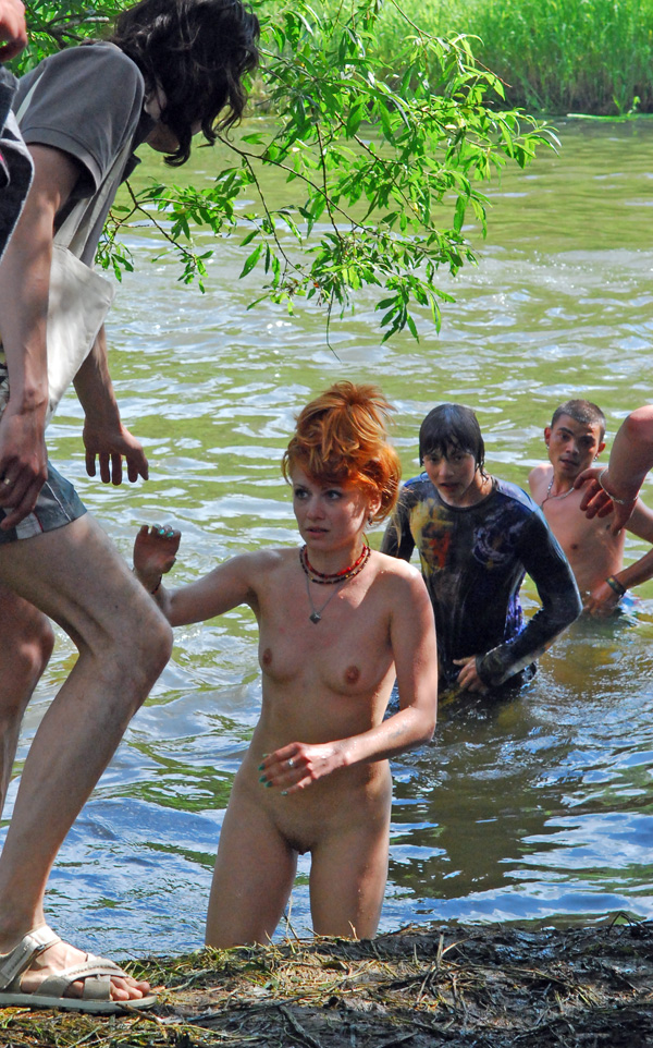 Redhead lady is playing in water without wearing any clothes.