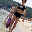 Short-haired brunette is undressing at public beach