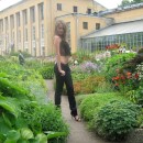 Sporty girl with piercing is undressing at botanic garden