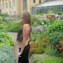 Sporty girl with piercing is undressing at botanic garden