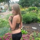 Sporty girl with piercing is undressing at botanic garden