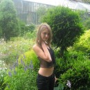 Sporty girl with piercing is undressing at botanic garden