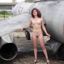 Naked curly girl walking in the aircraft museum