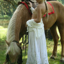 Petite blonde with small tits posing with horse