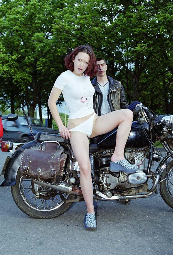 Red-haired girl undresses in front of a crowd of bikers