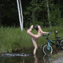 Sweet girl posing naked with a bicycle in nature