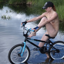 Sweet girl posing naked with a bicycle in nature