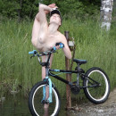 Sweet girl posing naked with a bicycle in nature