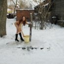 Naked girl collects water in the winter in Russian village