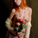 Beautiful red-haired girl with flowers is photographed naked