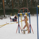 Busty brunette walks naked through the playground in winter