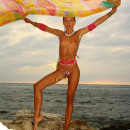 Charming young girl with bright bodypainting posing on the beach
