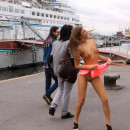 Crazy young girl undressing in the middle of bustling waterfront