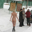 Naked blonde plays snowballs with her friends at winter road