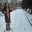 Short-haired brunette takes off her coat in the snow-covered park
