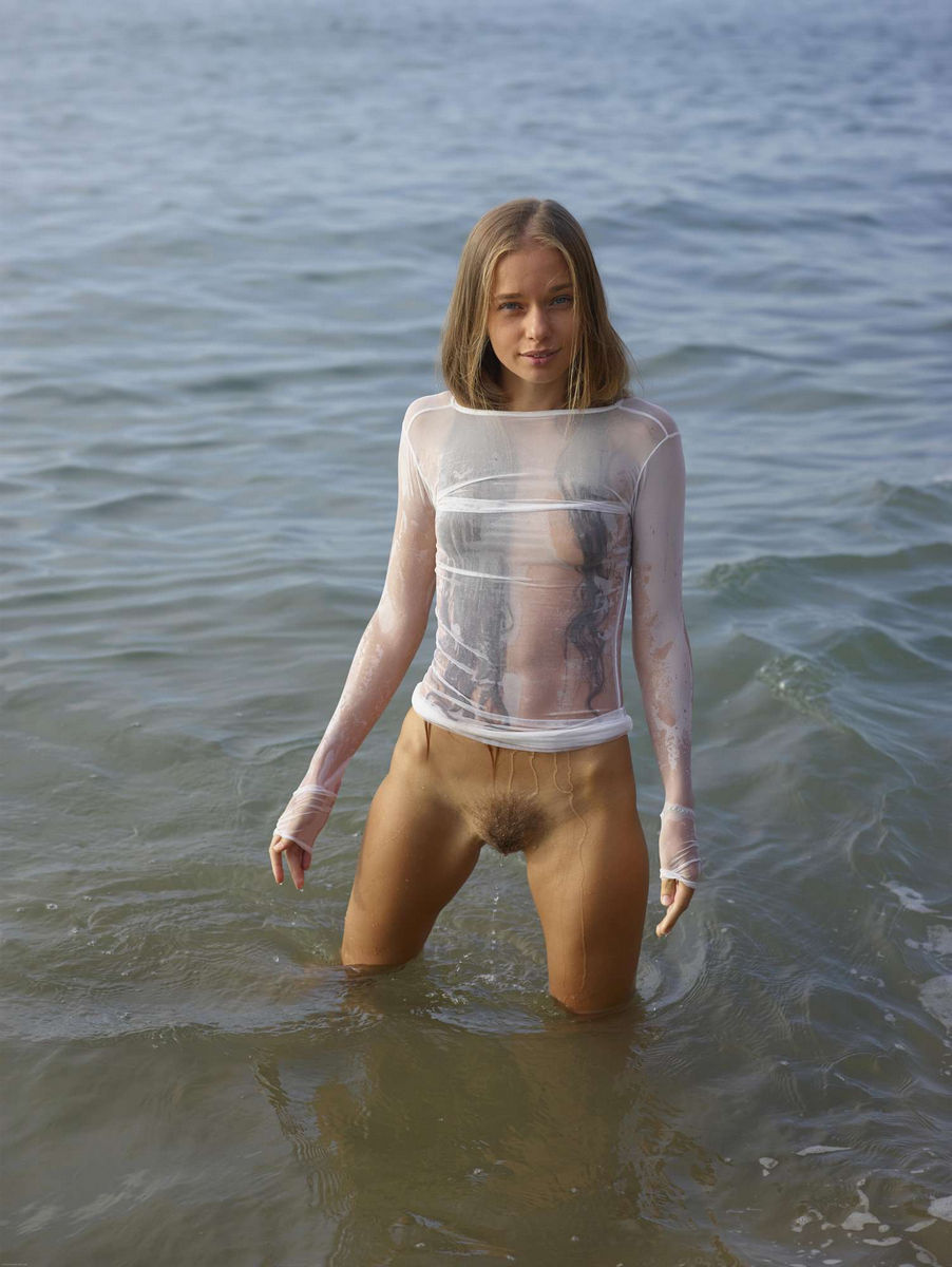 Young angel in very sexy transparent wet dress on the beach.