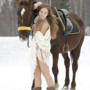Youthfull damsel posing with a pony in winter