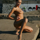 Naked brunette with a thin body on the concrete slabs near the sea