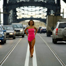 Smiling girl in pink transparent dress in the middle of bridge road