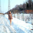 Girl in a transparent dress goes on winter road