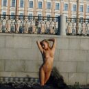 Naked blonde walks along the waterfront in the early morning