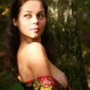 Smiling brunette with huge boobs walks in the woods