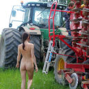 Russian girl undressing in front of a tractor on the field