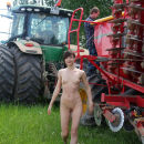Russian girl undressing in front of a tractor on the field