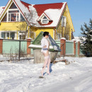 Brunette in white stockings walking at snow-covered village