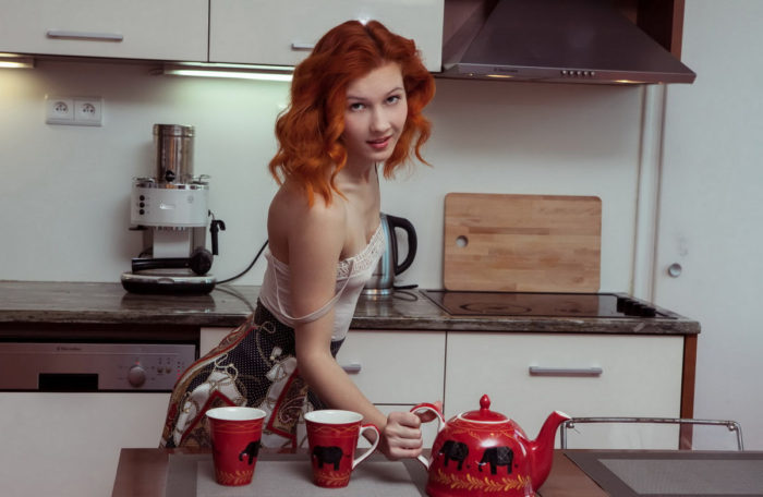 Fiery red-haired girl undressing in the kitchen
