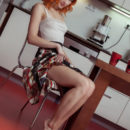 Fiery red-haired girl undressing in the kitchen