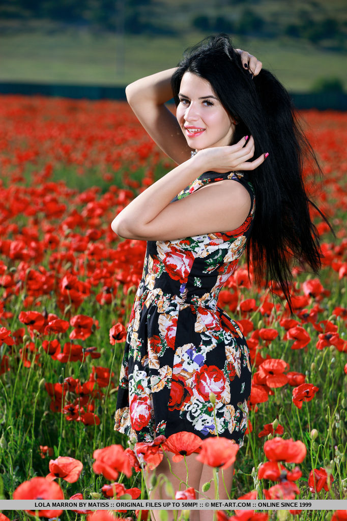With her long black hair, striking smile, and smooth, fair skin, Lola Marron's beauty stands out as she sprawls naked in the middle of a flower field