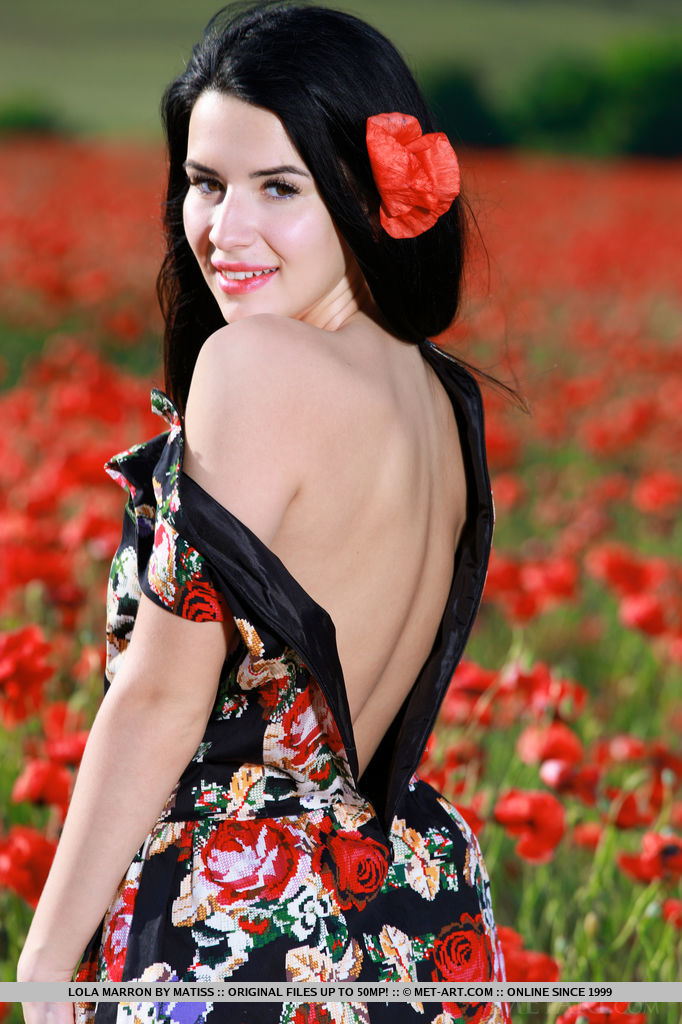 With her long black hair, striking smile, and smooth, fair skin, Lola Marron's beauty stands out as she sprawls naked in the middle of a flower field