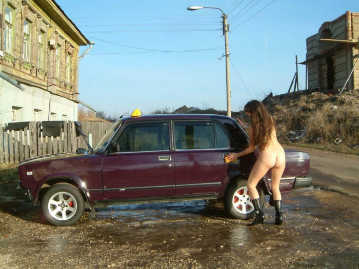 Girl with no clother washes taxi car outdoors