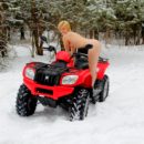 Short-haired blonde rides ATV at winter forest