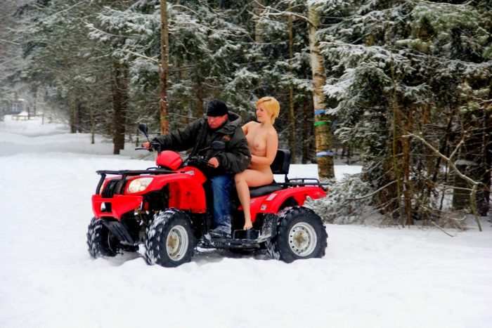 Short-haired blonde rides ATV at winter forest