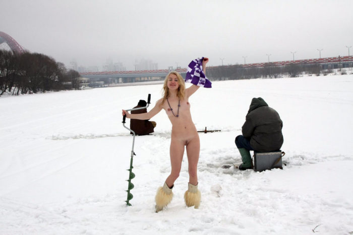 Young blonde helps fishermen at frozen river