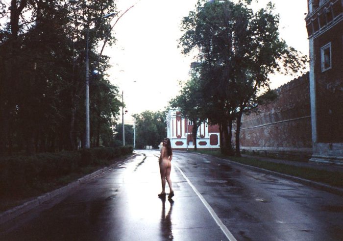 A girl without clothes walks a dog in the morning Moscow