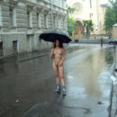 Curly girl in boots and an umbrella on a rainy street