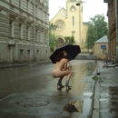 Curly girl in boots and an umbrella on a rainy street