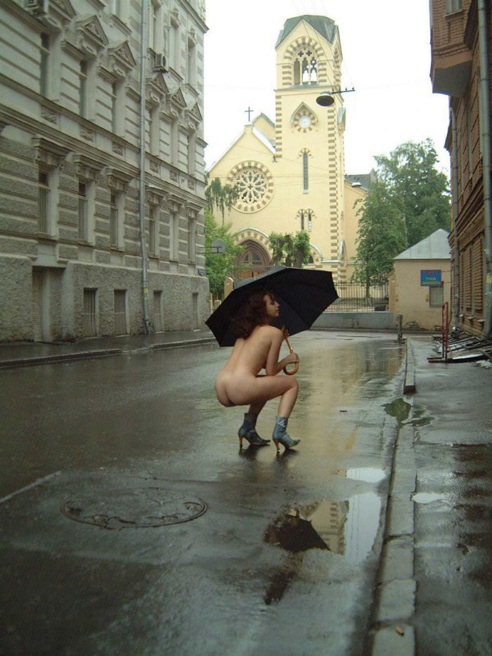 Curly girl in boots and an umbrella on a rainy street