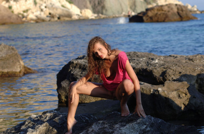 Curly-haired girl on a rocky shore
