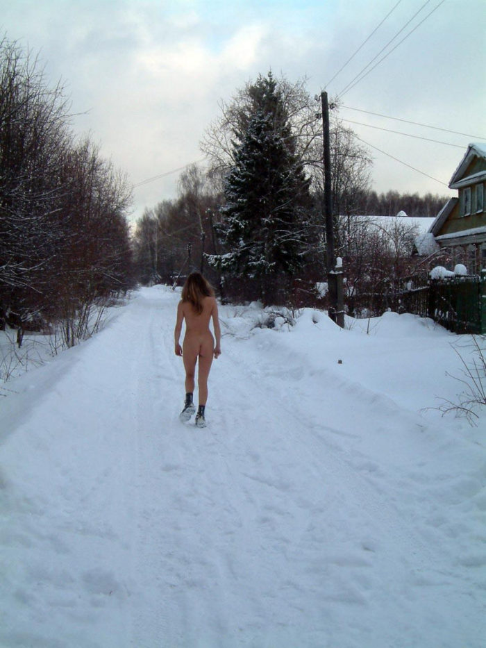 A girl takes off her boots in a snow-covered village