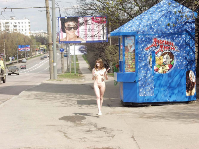 Naked girl buys some things in the kiosk