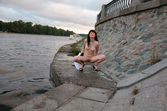 Girl Mila S takes off her clothes on the river bank