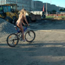 Naked blonde on bicycle at city center