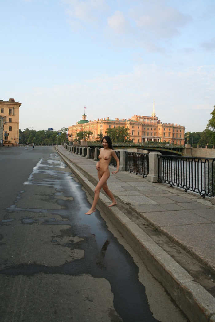Sweet brunette posing naked at river embankment